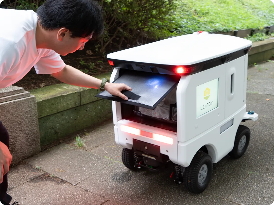 玄関先でLOMBYから荷物を受け取る様子